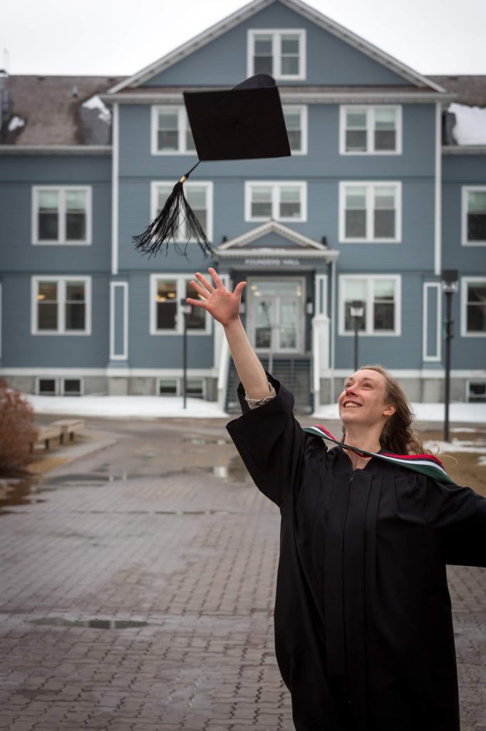 Undergraduate celebrating at Augustana Campus throwing hat in the air