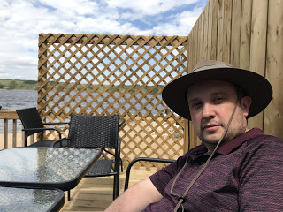 Bernard sits at a table on a patio with Manitou Lake in the background.