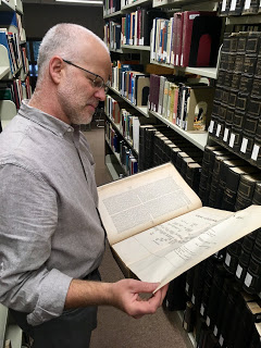 Librarian David Salz reading a book in the stacks of Rutherford Library