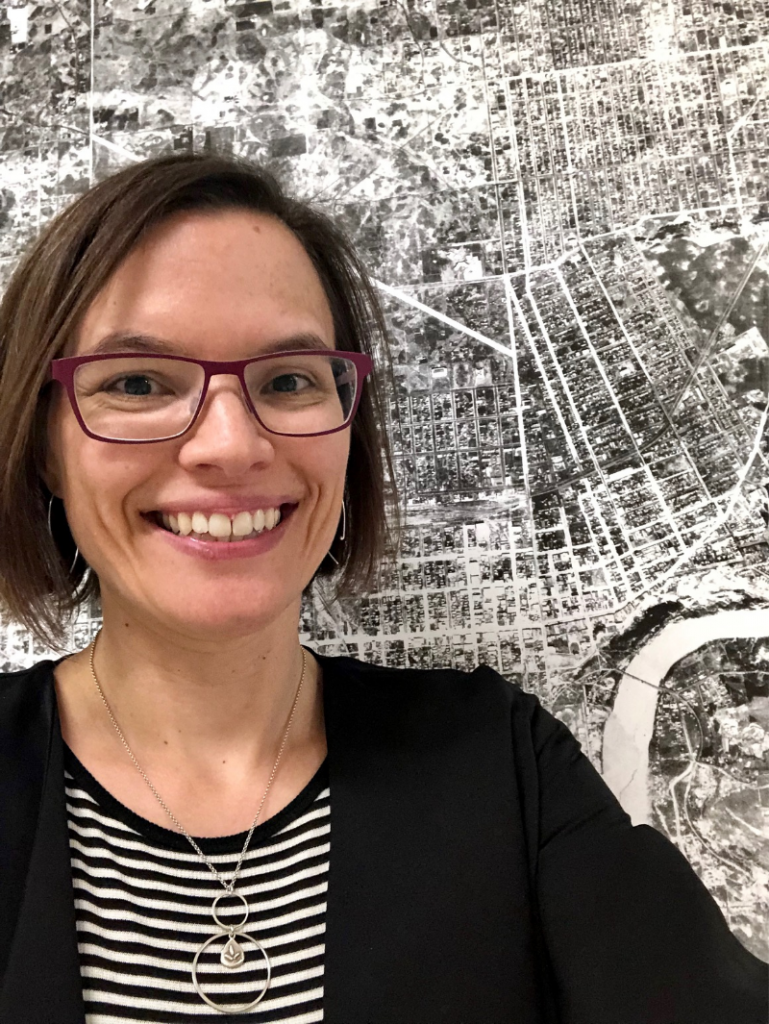 Shannon smiling in front of a map of Edmonton.