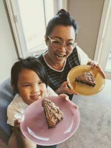 Sonya and her daughter hold slices of chocolate cake.