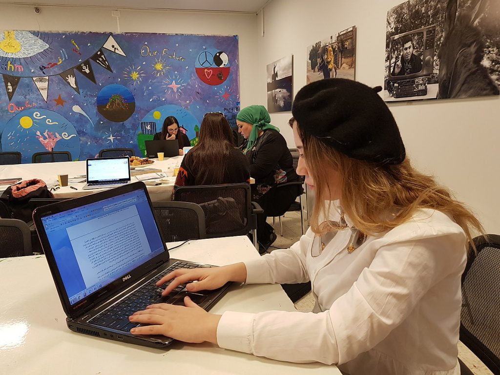 A woman sits at a computer and edits text.