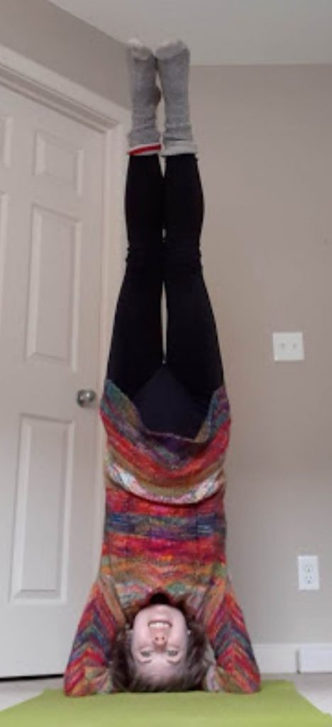 Natalya poses in a headstand on her yoga mat at home.