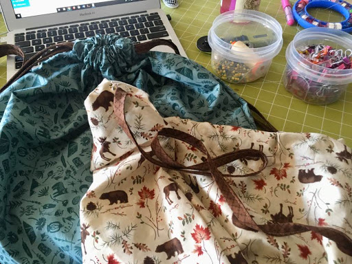 The author strings a tie through a home-sewn bag with pins, clips, and her laptop on the desk.