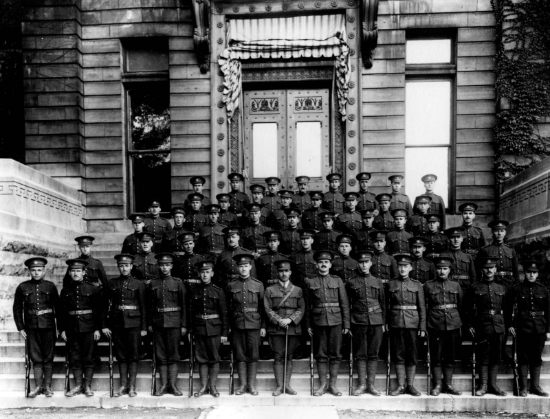 Four rows of soldiers stand on the steps in front of a building.