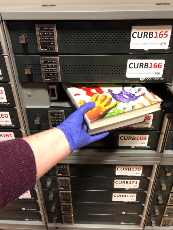 A hand puts books into a locker.
