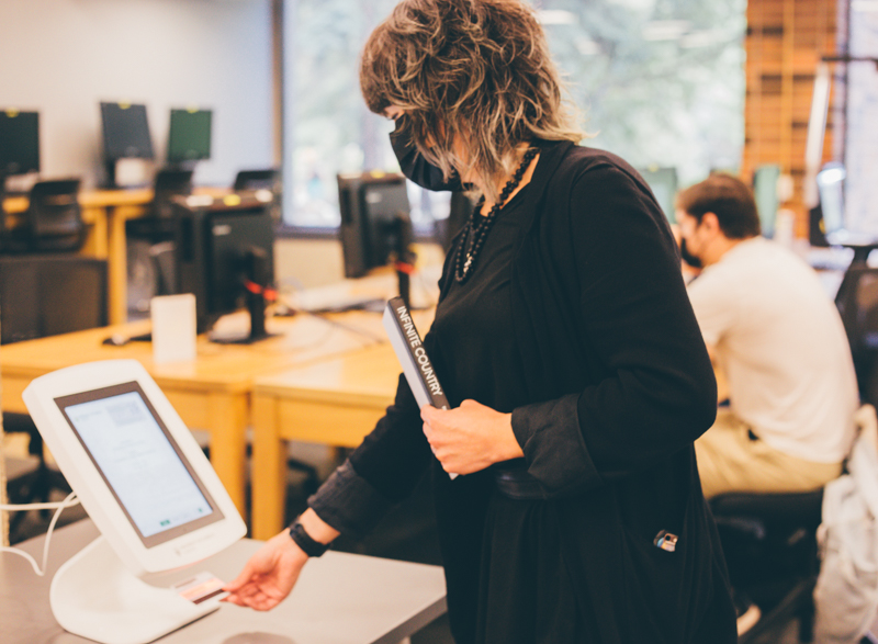 A U of A Library staff scans their ONEcard at the self-serve kiosk.